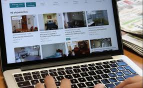 Persona buscando propiedades de alquiler en una página web desde un portátil, mostrando diferentes opciones de alojamiento.