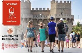 Grupo de turistas caminando frente a una fortaleza histórica, con una placa de registro de Vivienda de Uso Turístico (VT) de la Comunidad Valenciana, en Teresa Gestora de Alquiler